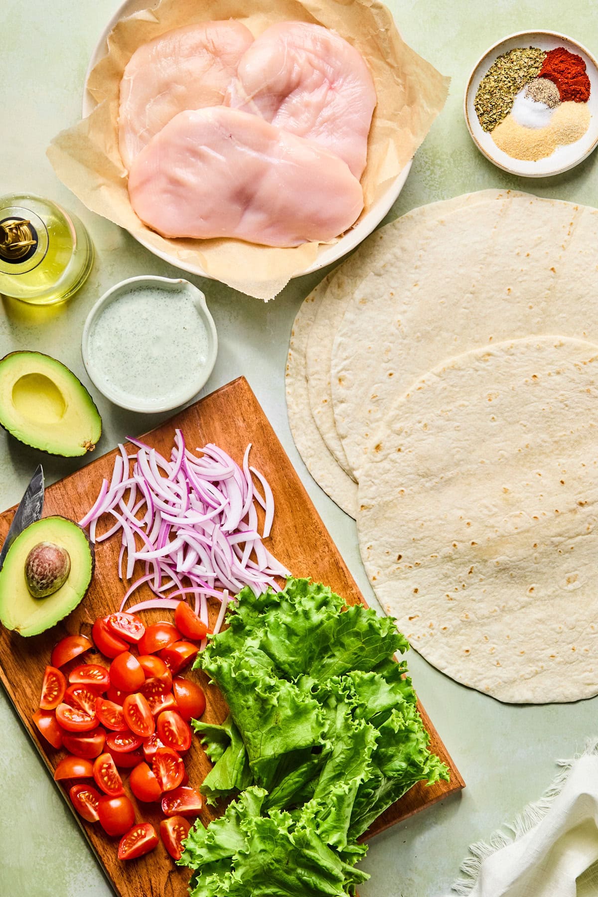 Grilled chicken wrap ingredients laid out on a light green countertop.