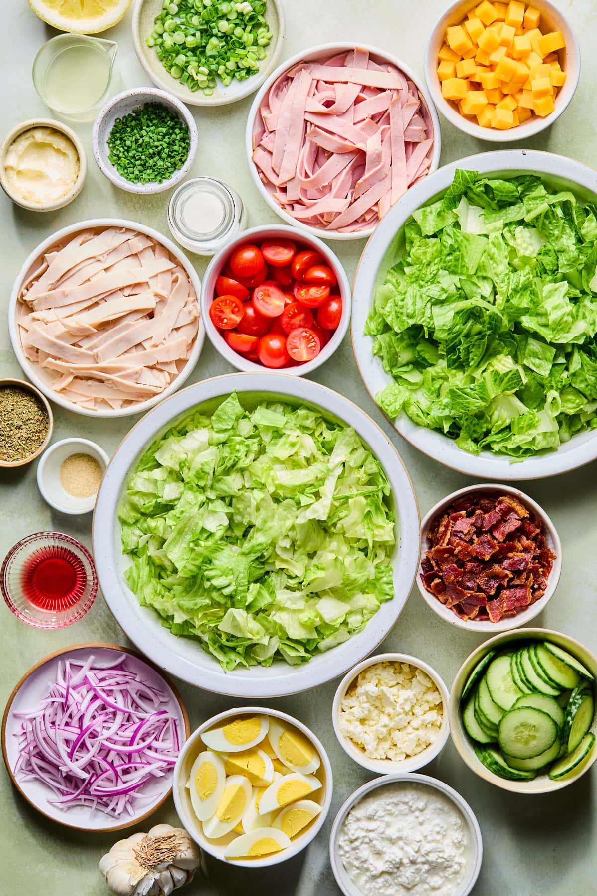 Chef's salad recipe ingredients in small bowls laid out on a countertop.