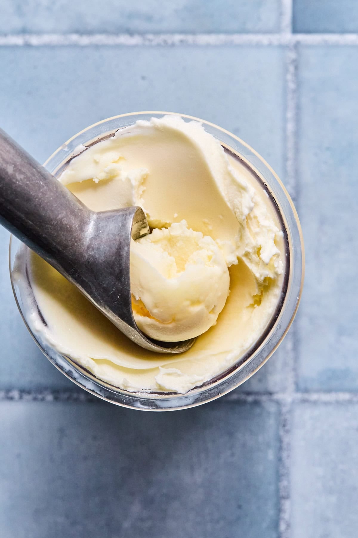 Blended Ninja Creami pineapple sorbet in the pint container with an ice cream scoop scooping a portion.