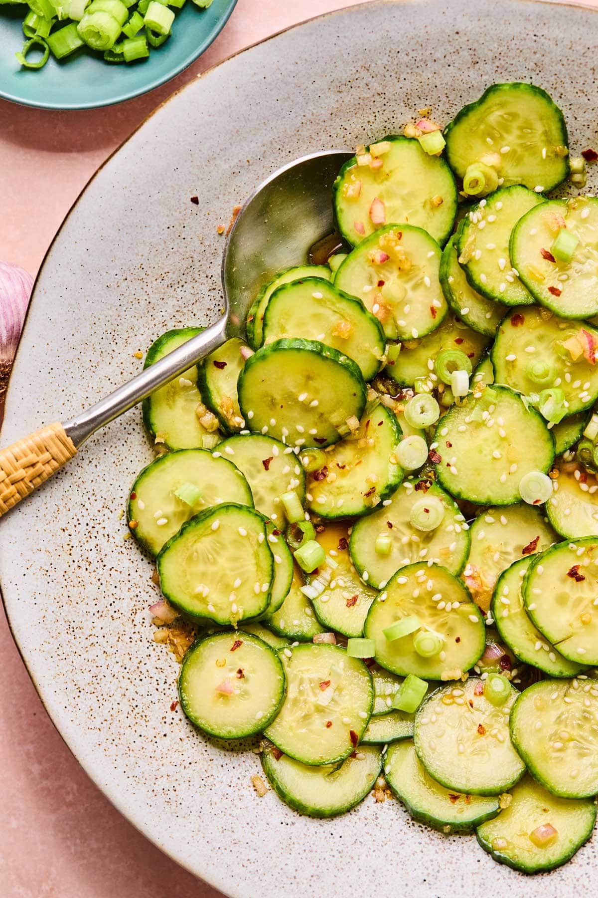 Asian cucumber salad tossed in a savory sesame dressing and marinating in a large bowl before serving.