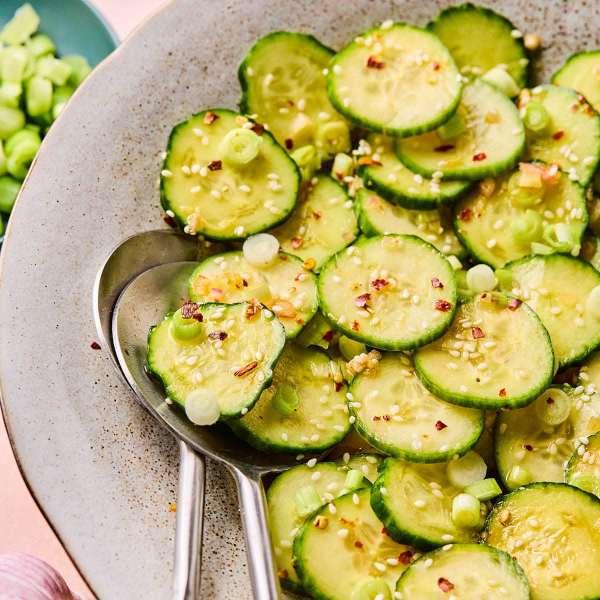Asian cucumber salad tossed in a savory sesame dressing and marinating in a large bowl before serving.