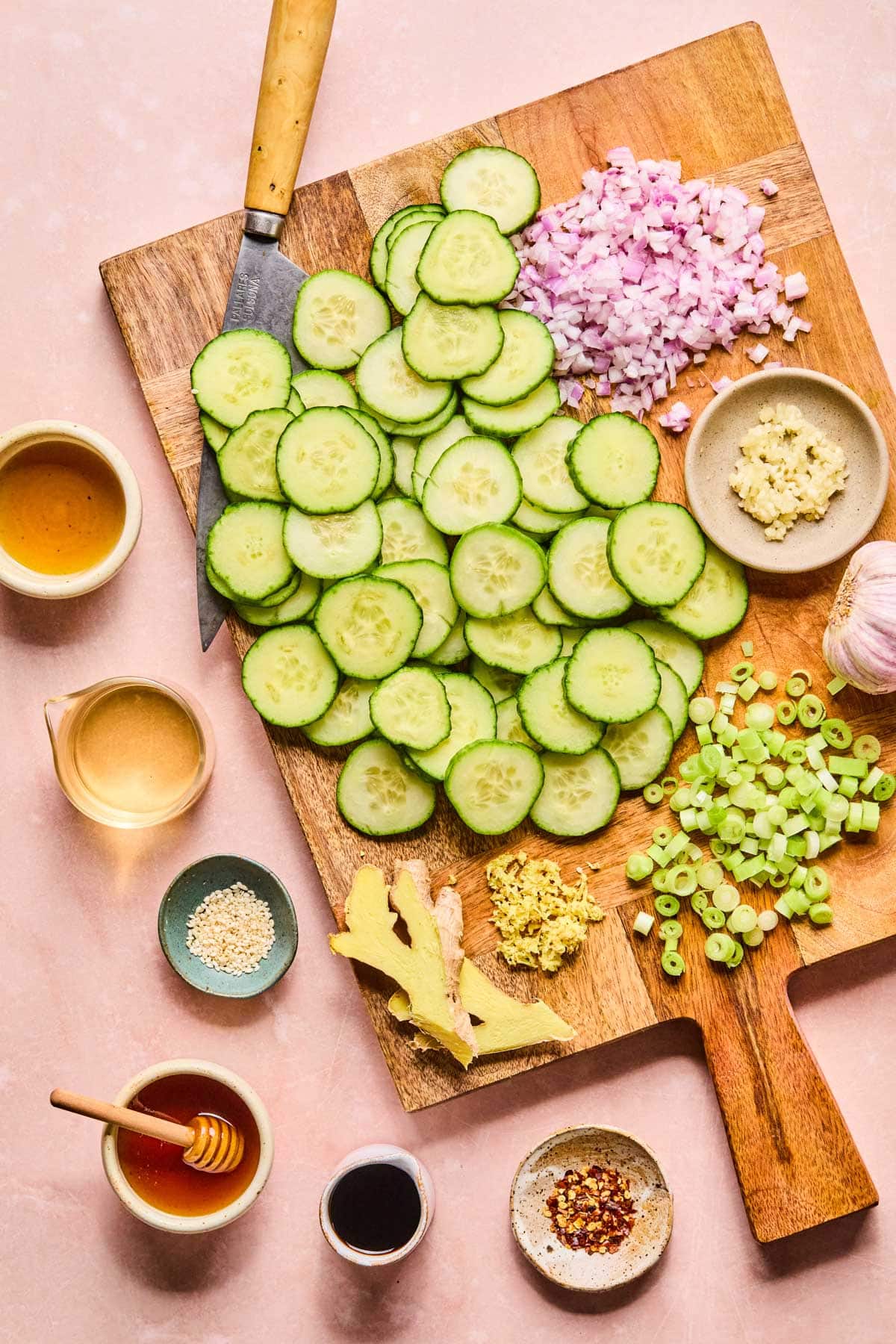 Asian cucumbers recipe ingredients laid out on a wooden cutting board.