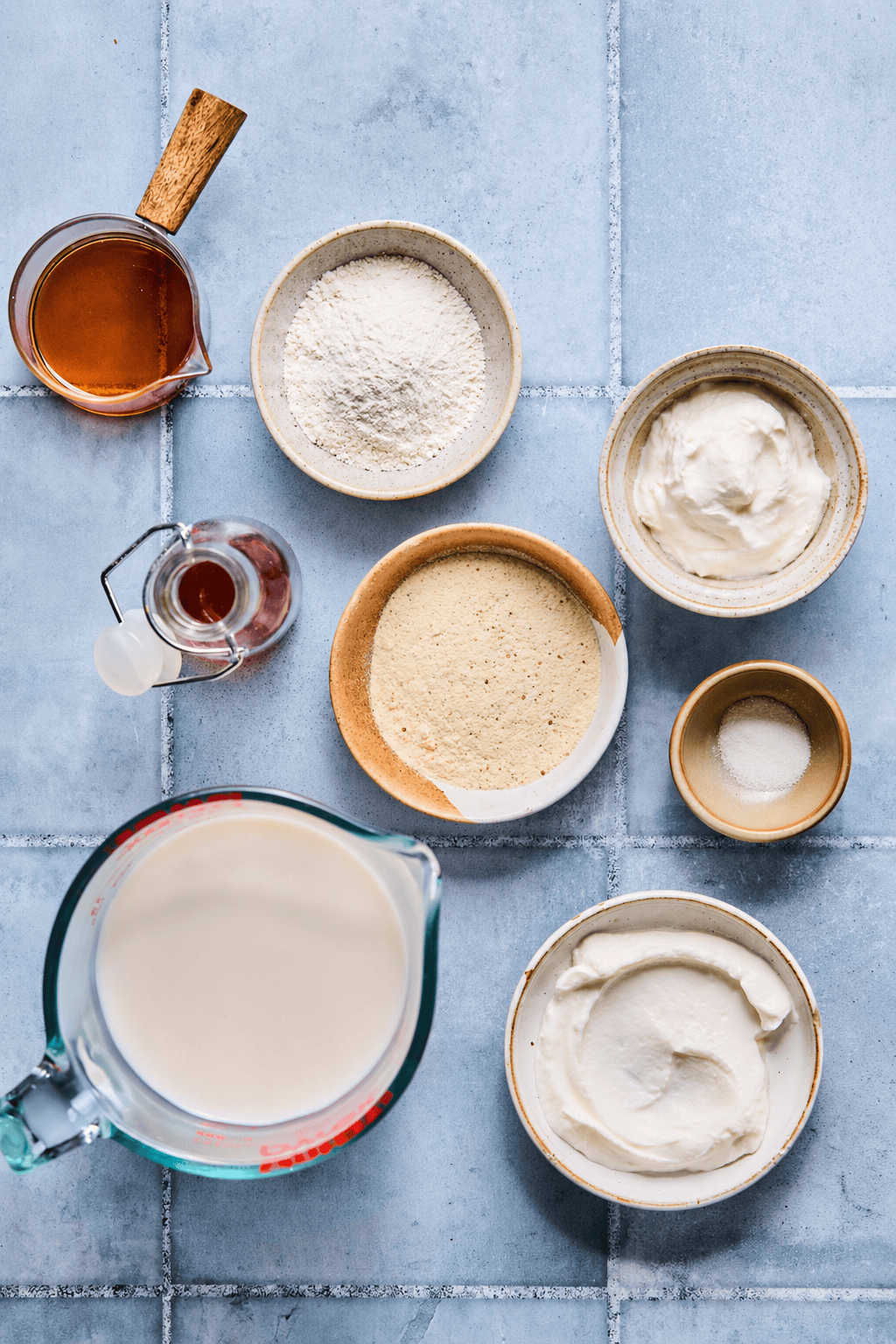 Ninja Creami vanilla ice cream recipe ingredients laid out in nesting bowls and measuring cups on a countertop.