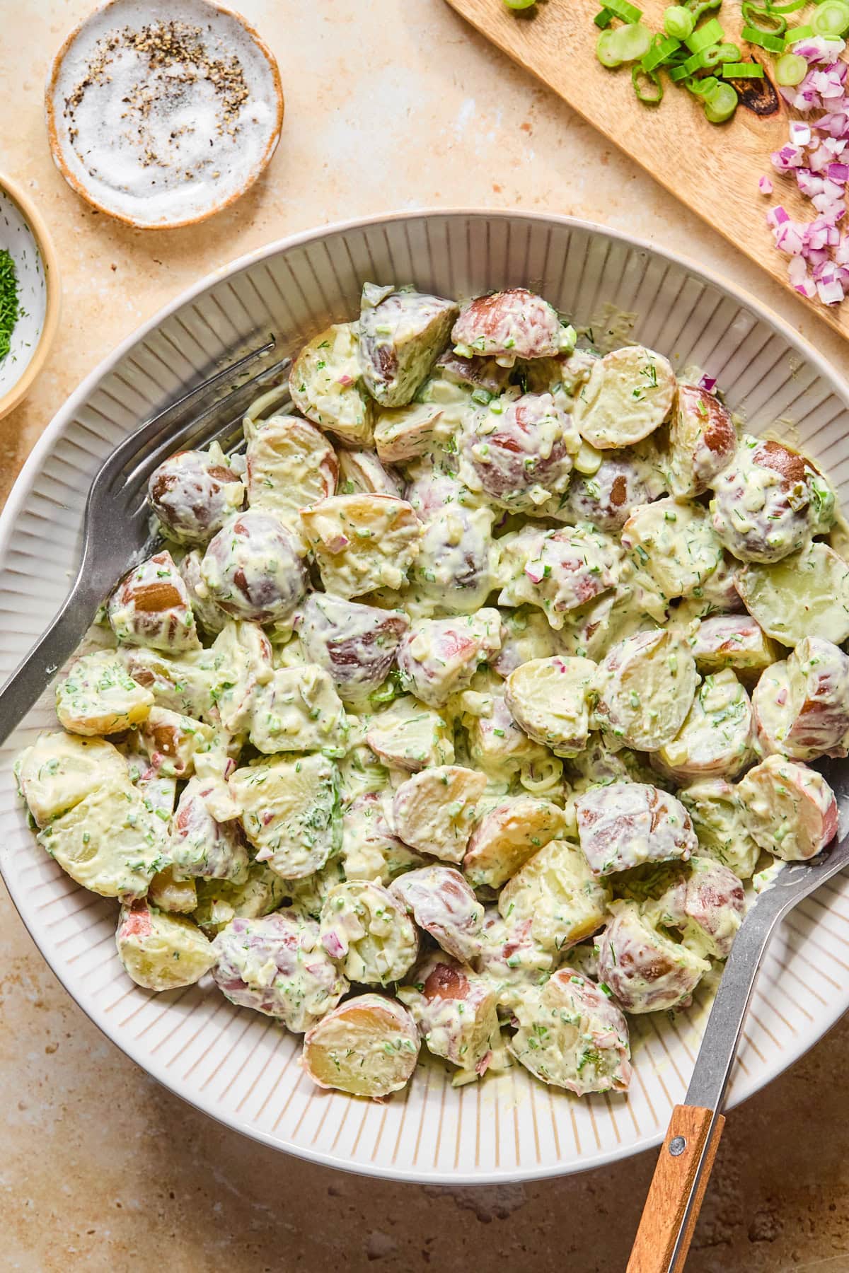 Chilled skin-on red potato salad served in a bowl and garnished with fresh dill and chives.