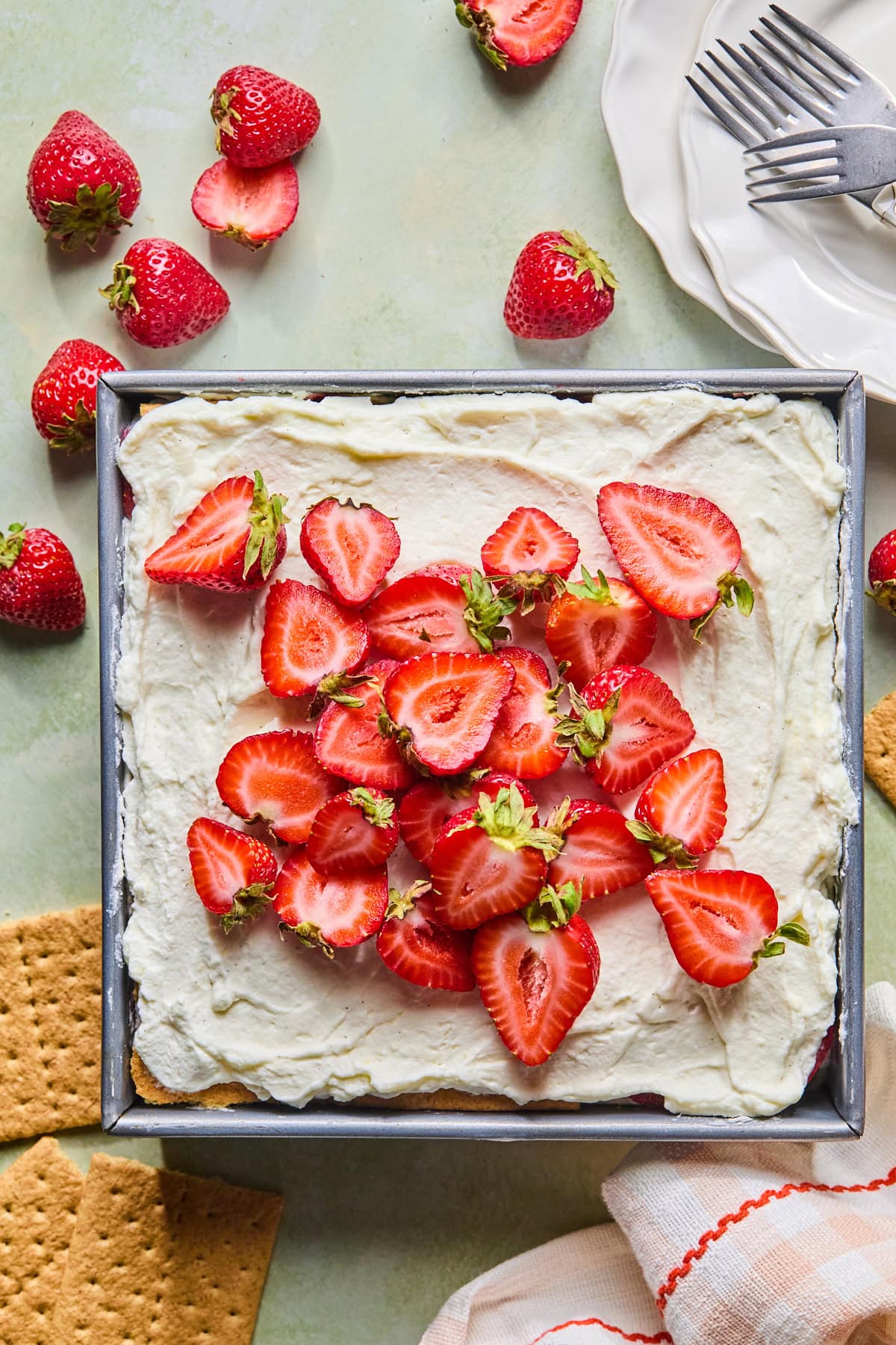 Strawberry icebox cake chilled in a baking dish and topped with fresh strawberries, ready to slice and serve.