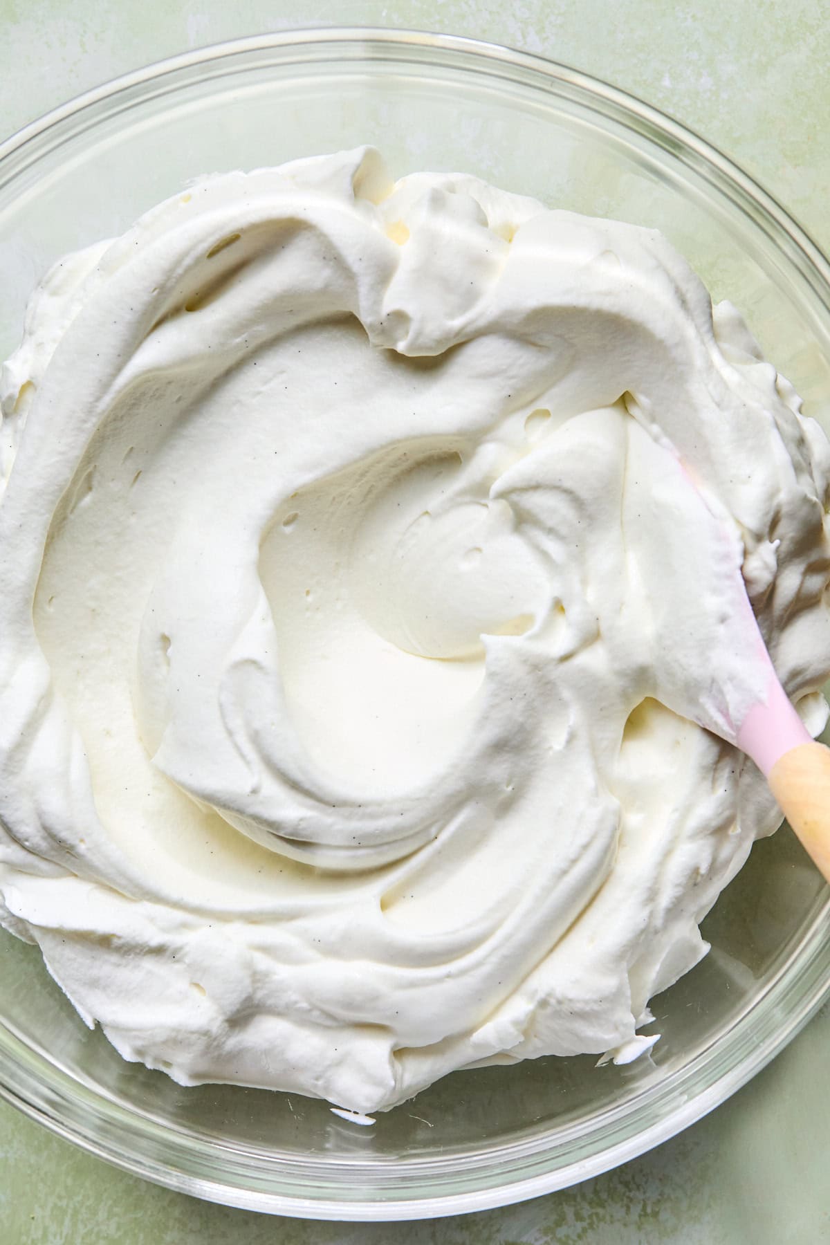 Heavy cream, powdered sugar, and vanilla whipped to stiff peaks in a mixing bowl.