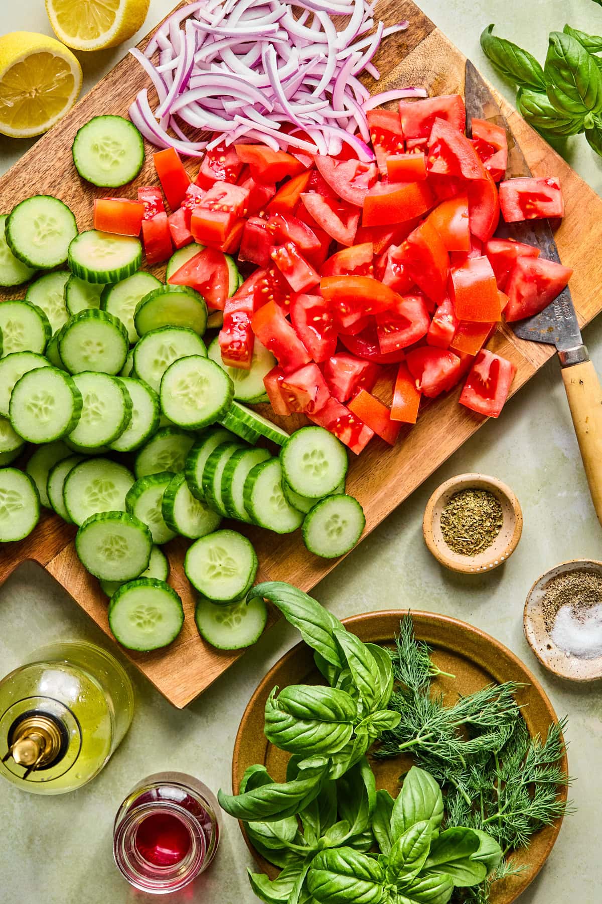 Tomato cucumber salad recipe ingredients chopped and laying on a wooden cutting board.