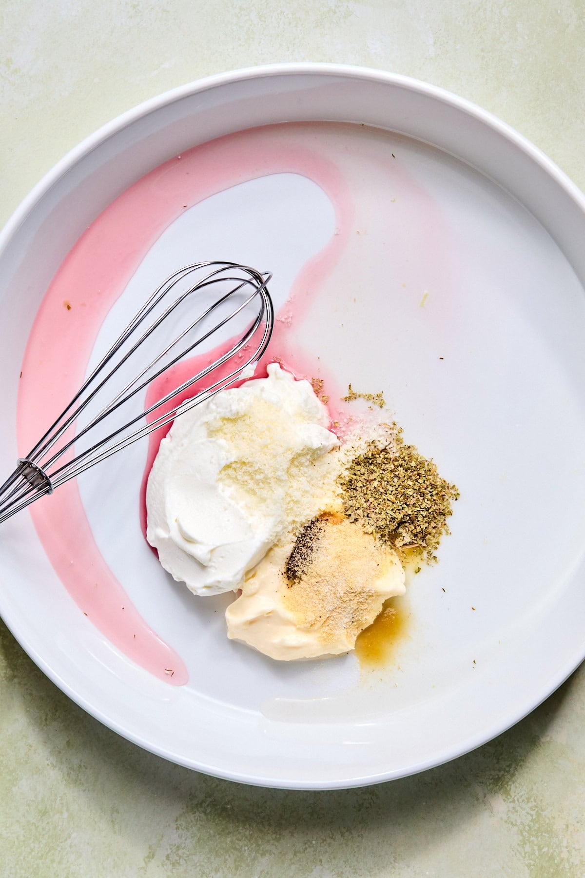 Mayonnaise, Greek yogurt, red wine vinegar, pepperoncini juice, Italian seasoning, garlic powder, onion powder, Parmesan cheese, salt, and black pepper combined in a large mixing bowl before whisking.
