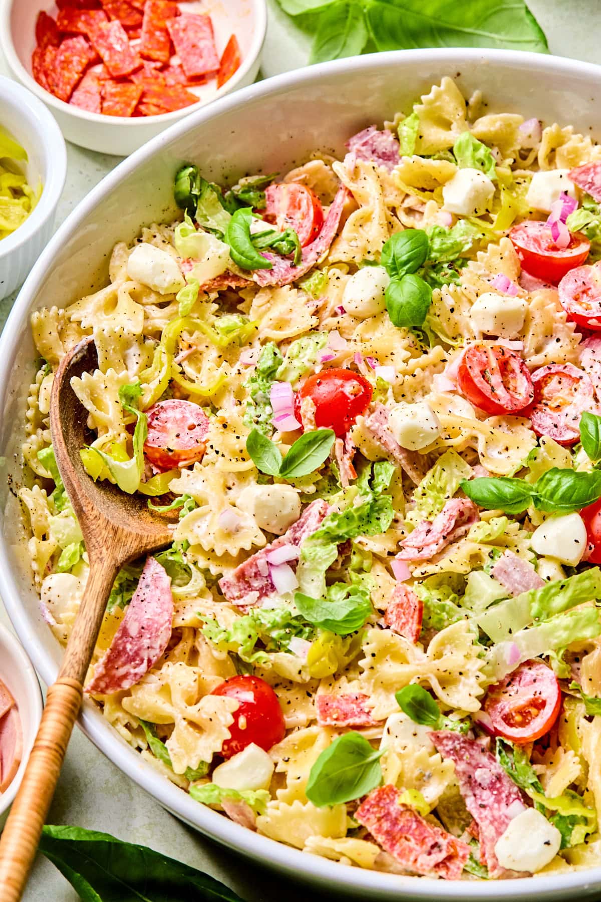 Close-up of Italian grinder pasta salad in a large serving bowl with wooden serving spoons.