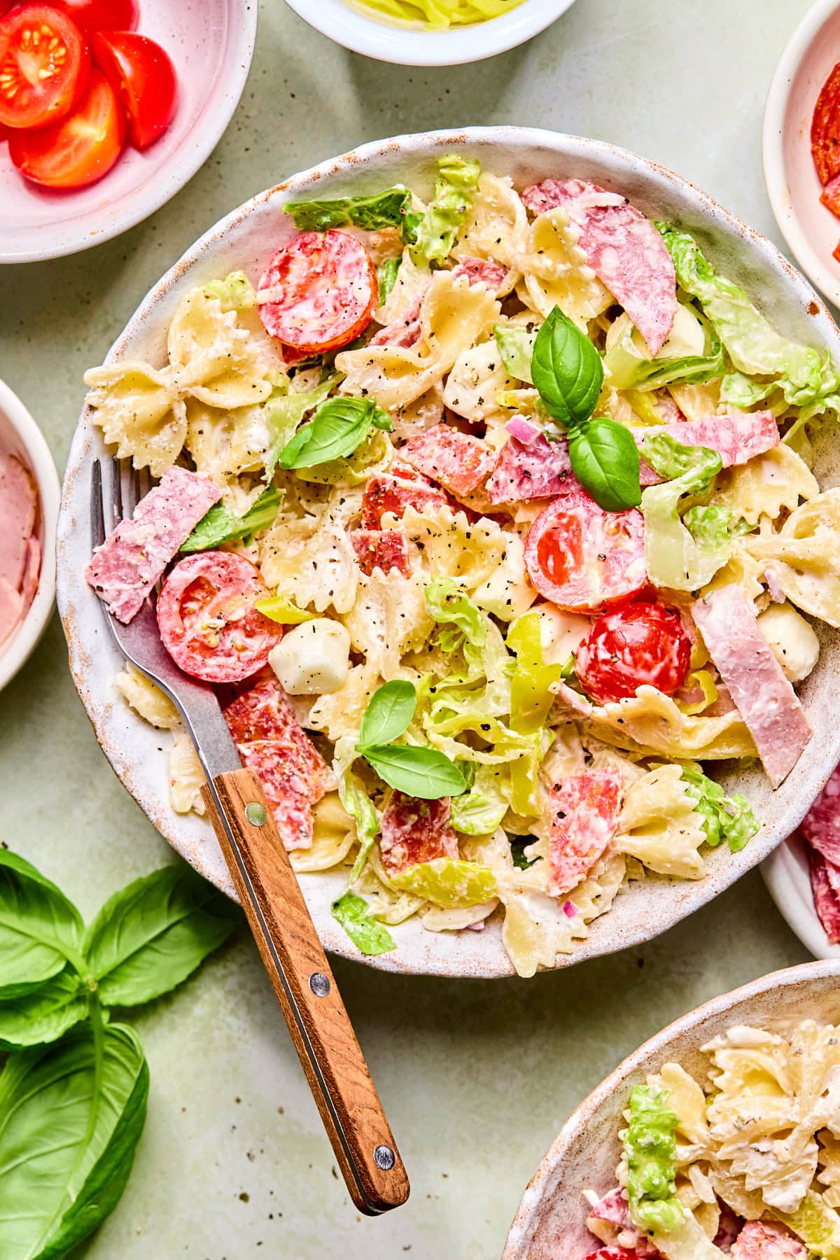 A small bowl of Italian grinder pasta salad with a fork ready for serving.