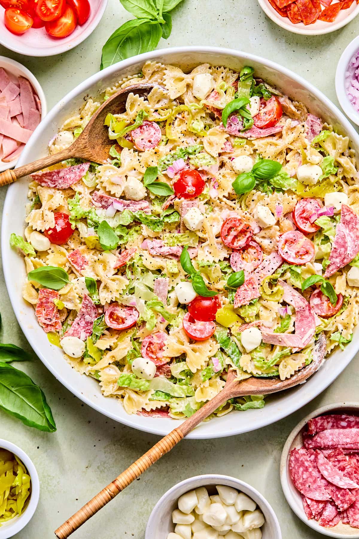 Italian grinder pasta salad in a large serving bowl with wooden serving spoons.