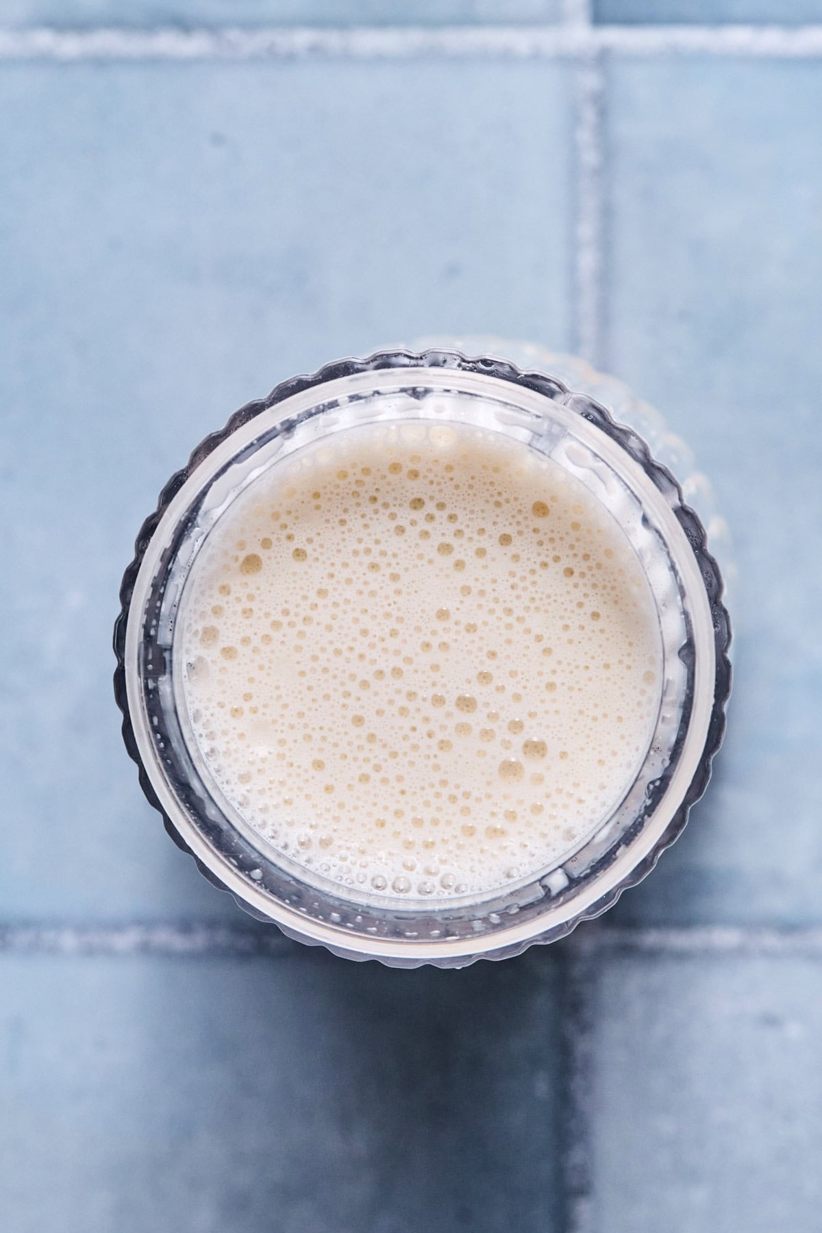 Blended vanilla ice cream ingredients in a Ninja Creami pint container, mixed until completely smooth and liquid before freezing.