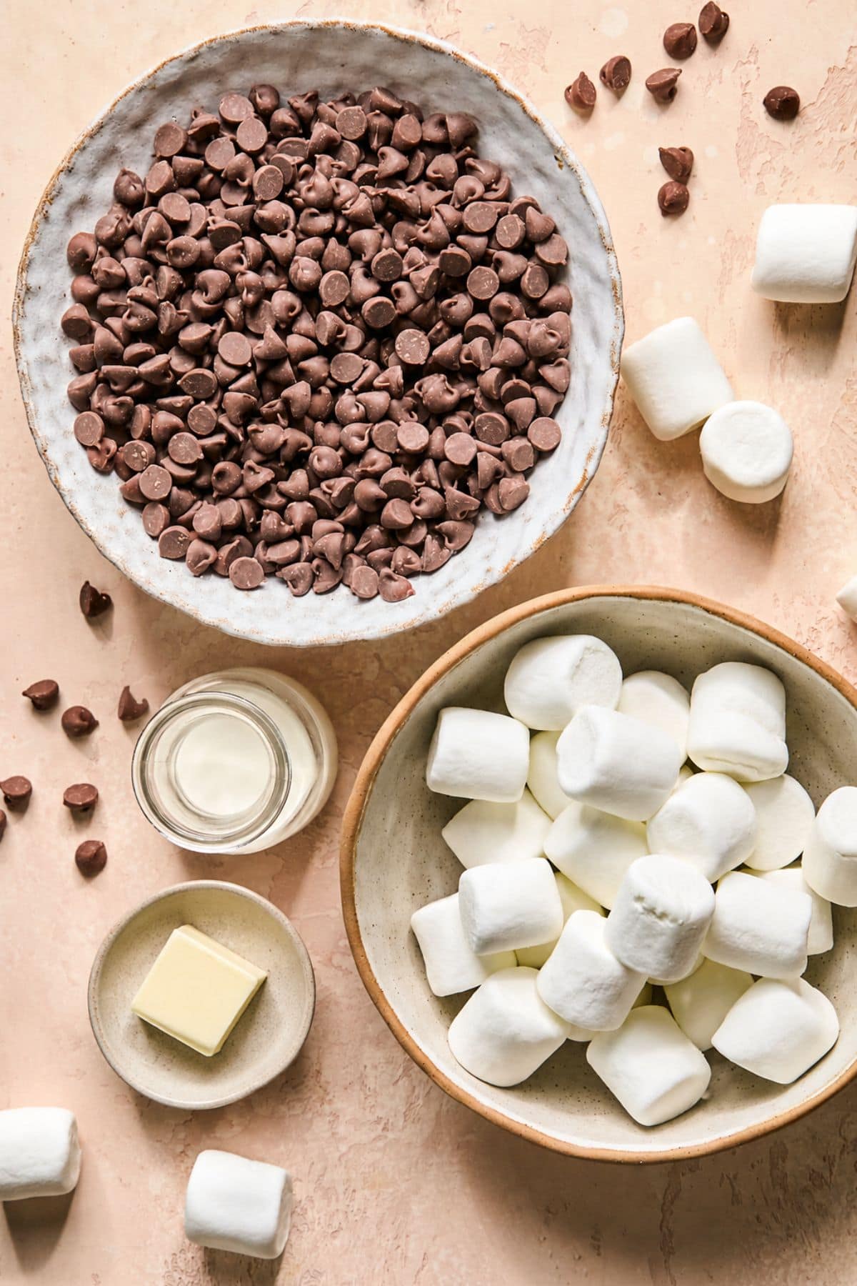 Smores dip recipe ingredients laid out in decorative bowls on a counter top.