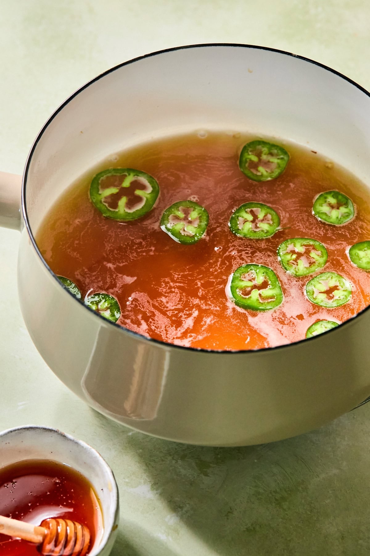 Water, honey, and sliced jalapeños simmering together in a small saucepan to make homemade jalapeño honey syrup.