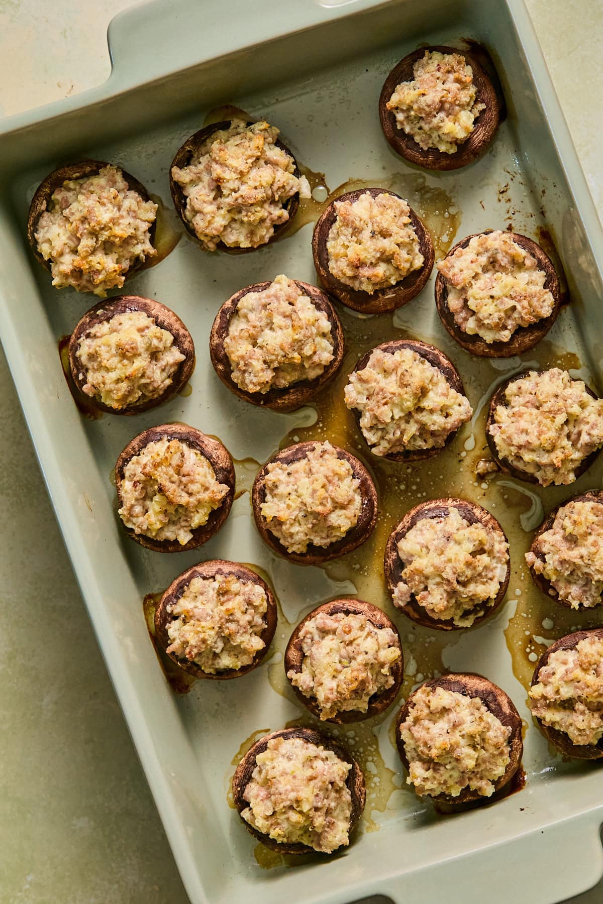 Baked sausage stuffed mushrooms arranged in a single layer in a baking dish.