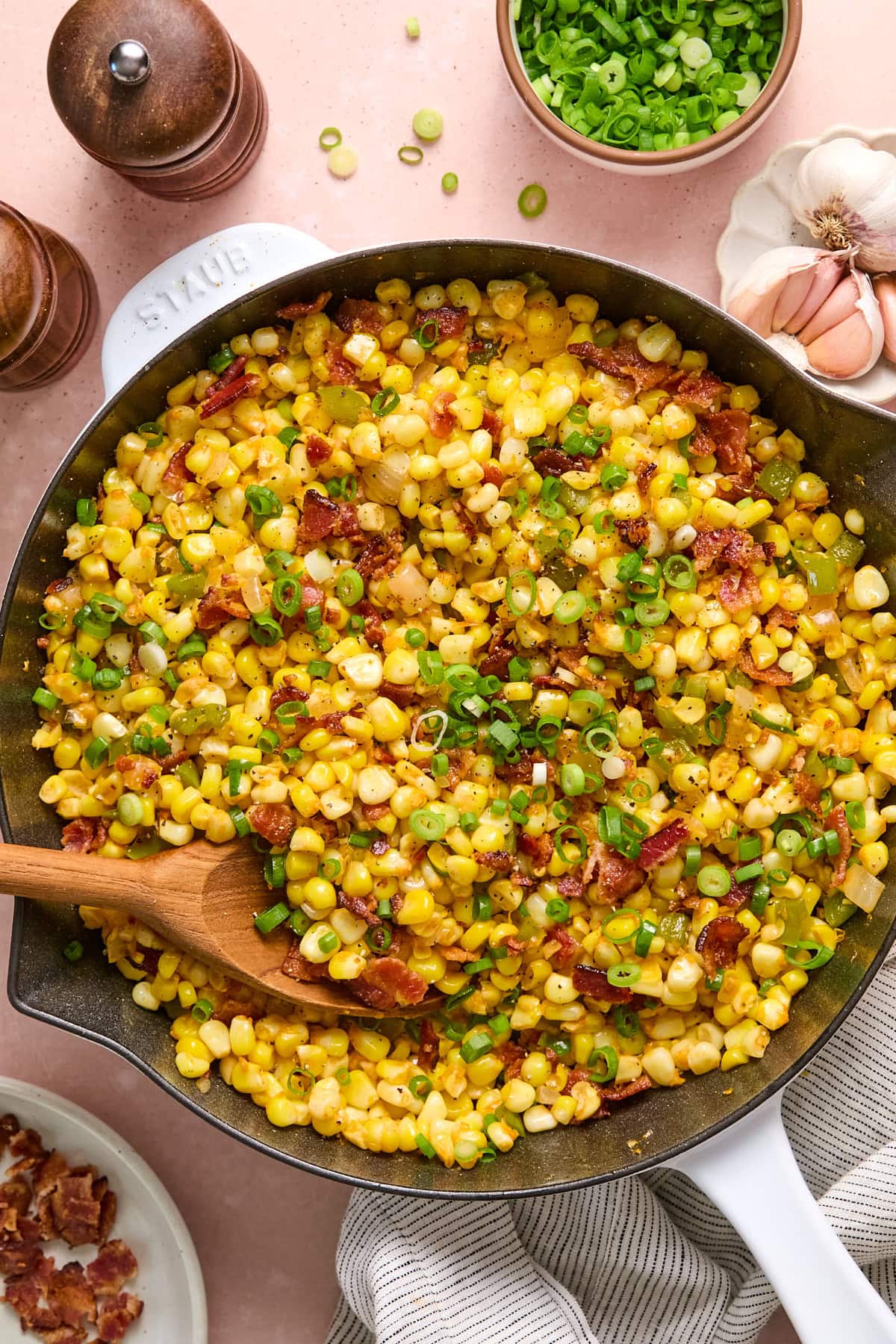 Friend corn recipe in a large skillet on a light pink countertop.