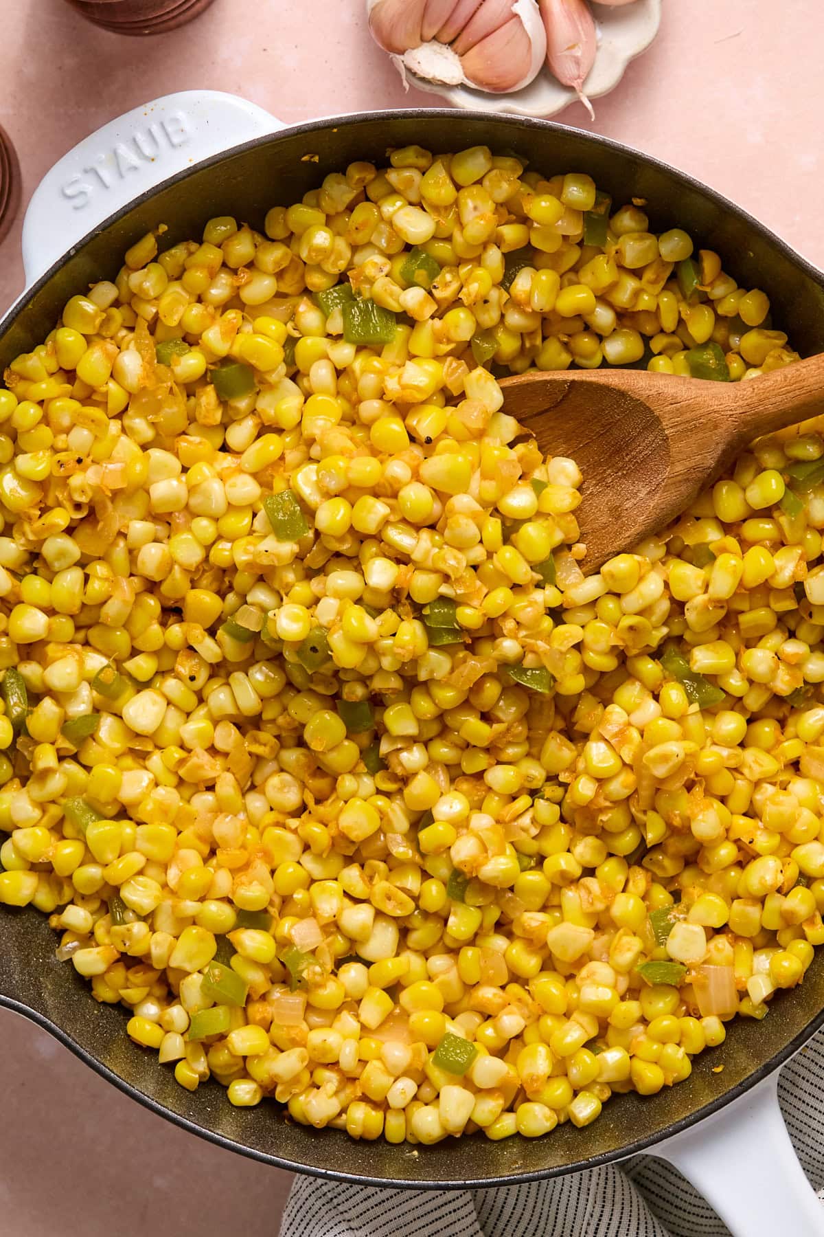 Corn added to the skillet and seasoned with paprika, salt, and pepper spread in an even layer.