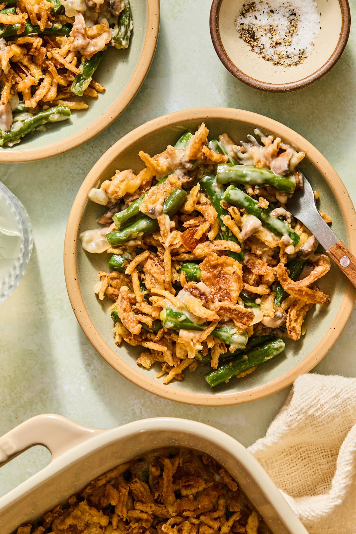 A serving of the homemade green bean casserole on a dish with a fork.