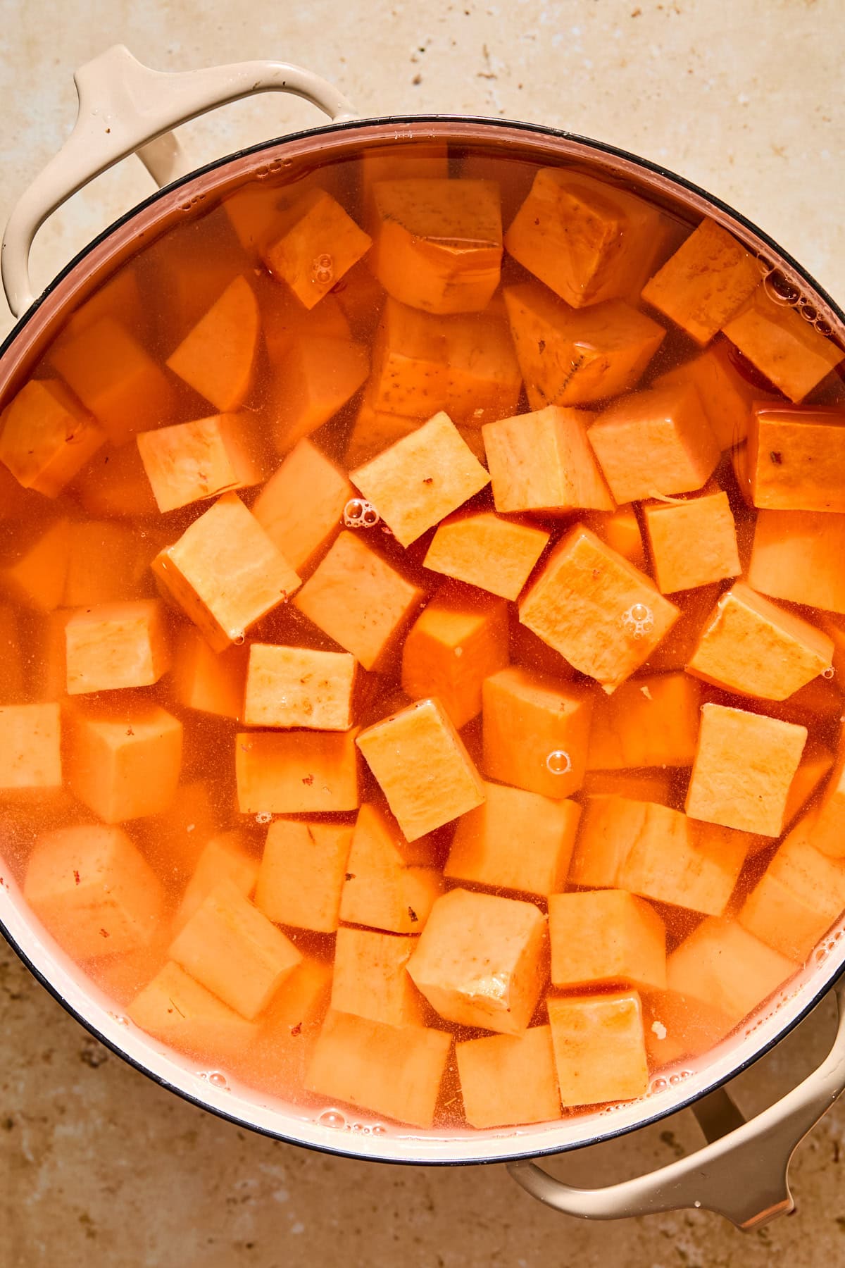 Raw sweet potato cubes in a large pot covered in water.