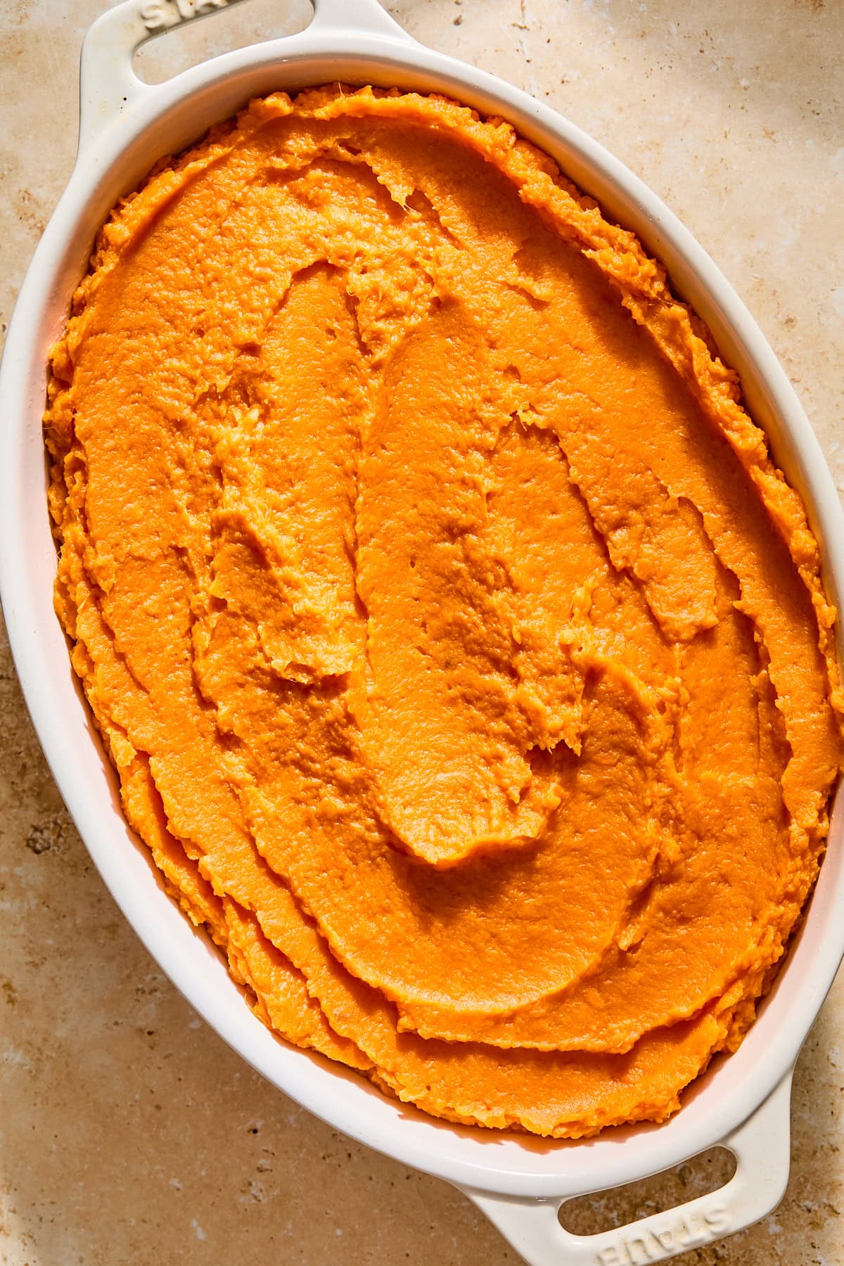 Sweet potato casserole filling lining an oval baking dish before adding the pecan topping.