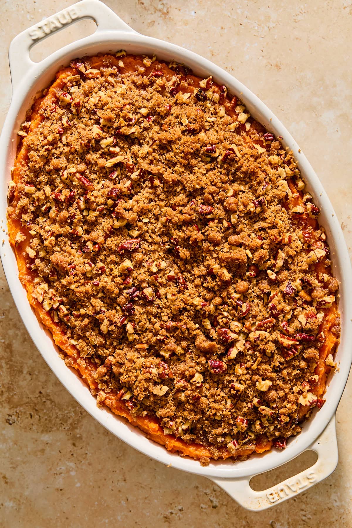 A sweet potato casserole in an oval dish topped with pecan streusel.