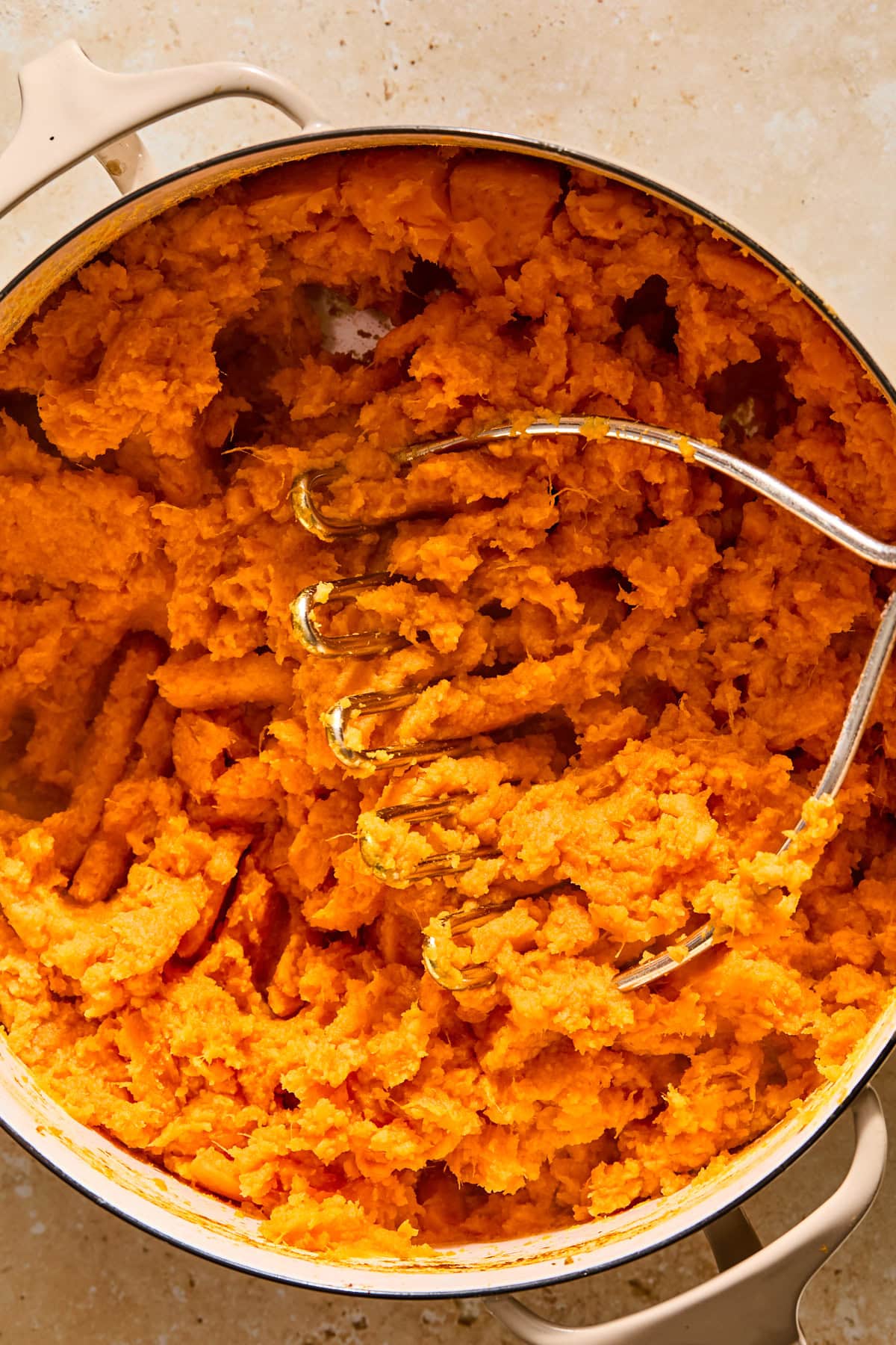 Mashing sweet potatoes with a potato masher.